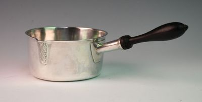 a silver sauce pot with a wooden handle on a white table