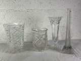 three glass vases and a candle holder on a table