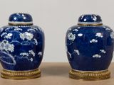 two blue vases with white flowers on them sitting on a table