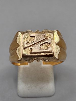 a close up of a gold signet ring on a white stand