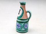 a small ceramic vase with a handle on a white surface