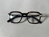 des lunettes noires et écaille posées sur une surface blanche, sur fond blanc