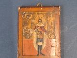 une vieille icône en bois représentant un homme tenant une croix sur un fond bleu