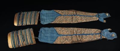 trois morceaux de tissu à rayures dorées et bleues reposent sur une surface noire