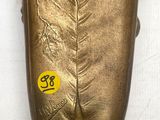 un vase en or orné d'une feuille, posé sur une table
