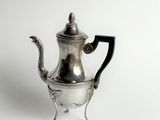 une théière ancienne en argent, avec une anse noire sur fond blanc
