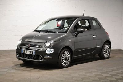 La petite voiture grise est garée dans le garage, sur le sol à carreaux.