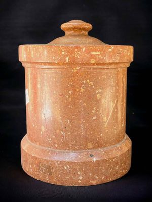 a close up of a stone container with a lid on a black background