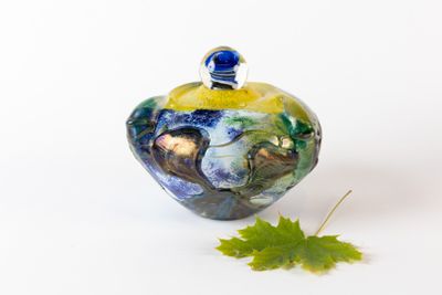 une petite décoration en verre avec une feuille posée par terre