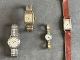 trois montres et un bracelet de montre sont posés les uns à côté des autres