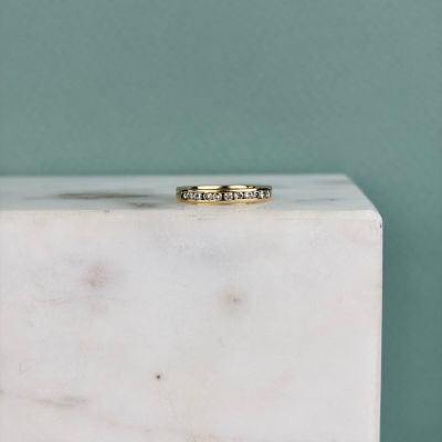 un gros plan d'une bague en or posée sur un bloc de marbre blanc