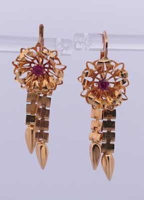 une paire de boucles d'oreilles en or et rubis exposée dans une vitrine