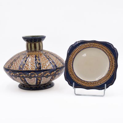 two vases and a plate on display on a stand