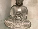 une statue de Bouddha assis sur une table en verre