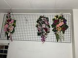three flower arrangements hanging on a wire rack in a room