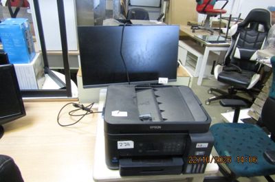une imprimante posée sur un bureau, à côté d'un écran d'ordinateur