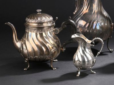 trois théières en argent et une cafetière en argent posées sur une table