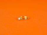 a gold ring with a diamond on an orange surface
