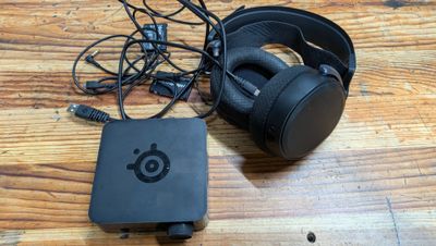 une boîte noire avec un casque et un chargeur posée sur une table en bois