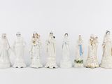 several figurines of people are lined up on a white surface