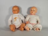 two dolls sitting next to each other on a table