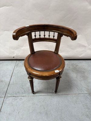 une chaise en bois avec une assise en cuir, posée sur un sol carrelé