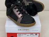 une paire de chaussures noires et roses, doublées de fourrure, posées sur une boîte