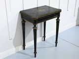 une petite table au plateau noir posée sur un sol blanc