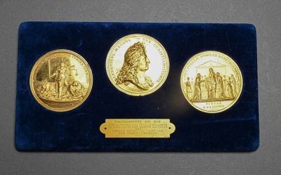 a close up of three gold coins with a plaque on a table