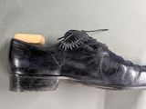a pair of shoes hanging on a wall with a shoe brush