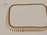 gros plan d'un collier en or sur une surface blanche