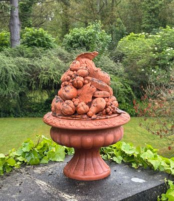 a statue of a bird sitting on top of a bowl of fruit