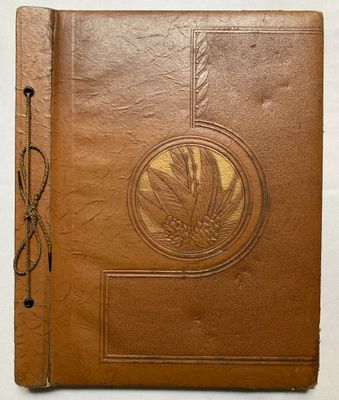 un vieux livre en cuir marron dont la couverture est ornée d'un motif de feuilles