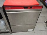 Une personne se tient dans une cuisine dont le plan de travail est rouge.