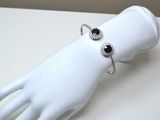 une main de mannequin blanche portant un bracelet noir et blanc