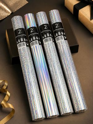 quatre rouleaux de papier d'argent posés sur une table, à côté d'un coffret cadeau