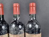 three bottles of red wine sitting on top of a wooden table