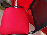 a red chair with a black seat in front of a red wall