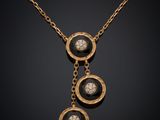 un collier en or auquel sont suspendues trois pierres noires et blanches