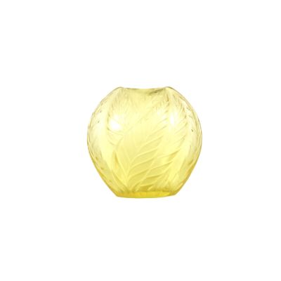 un vase en verre jaune orné d'un motif de feuilles
