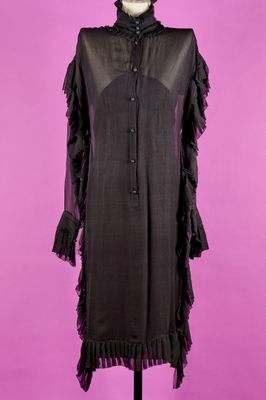 une robe noire posée sur un mannequin, sur fond rose