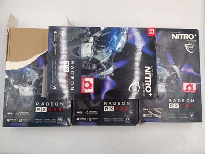 trois boîtes de cartes graphiques Nirox Radeon de la série RX destinées au gaming, posées sur une table