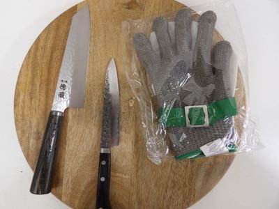 a cutting board with a pair of gloves and a knife on it