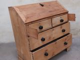 a small wooden chest of drawers on a concrete floor