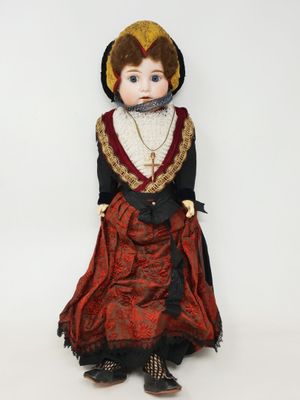 un gros plan d'une poupée portant une robe rouge et un chapeau noir