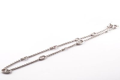 un gros plan sur une paire de bracelets à chaîne en argent sur fond blanc