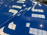 a close up of a blue car with a reflection of a building