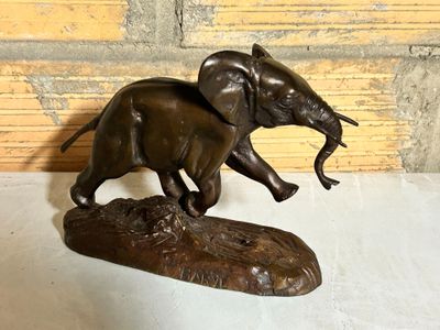 bronze statue of an elephant on a log with a fish in its mouth