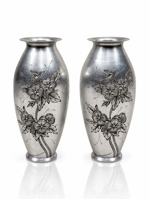 pair of silver vases with floral designs on them on a white surface