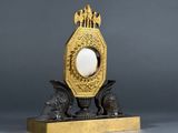a gold clock with a white egg in the middle of it